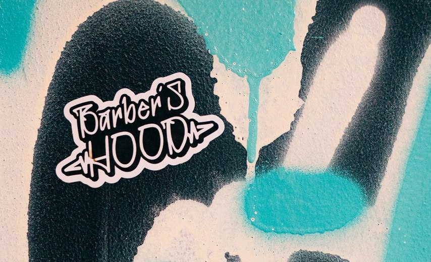 Sticker de Barber's Hood sobre el graffiti del local